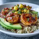 Fresh Shrimp and Creamy Avocado Bowls with Zesty Mango Salsa and Lime Chili Sauce shine with lime wedges for serving in this colorful dinner.