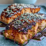 Pan-seared salmon glazed with honey sriracha sauce served over rice with crisp veggies and creamy avocado in a vibrant bowl.  