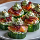 Fresh cucumber bites topped with creamy cheese and smoked salmon, garnished with dill and capers for an elegant appetizer.