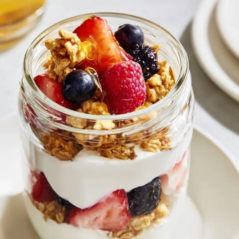 Close-up of a delightful berry parfait, featuring fresh berries, Greek yogurt, and golden granola, ready to eat.