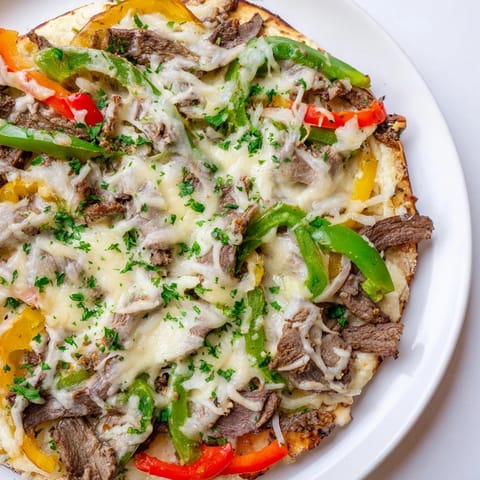 Golden-crusted Philly cheesesteak pizza, loaded with savory steak and creamy, bubbling cheese, ready to eat.