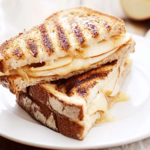 A golden-brown Smoked Gouda & Apple Grilled Cheese sandwich, featuring melted cheese and thin apple slices between buttery sourdough.