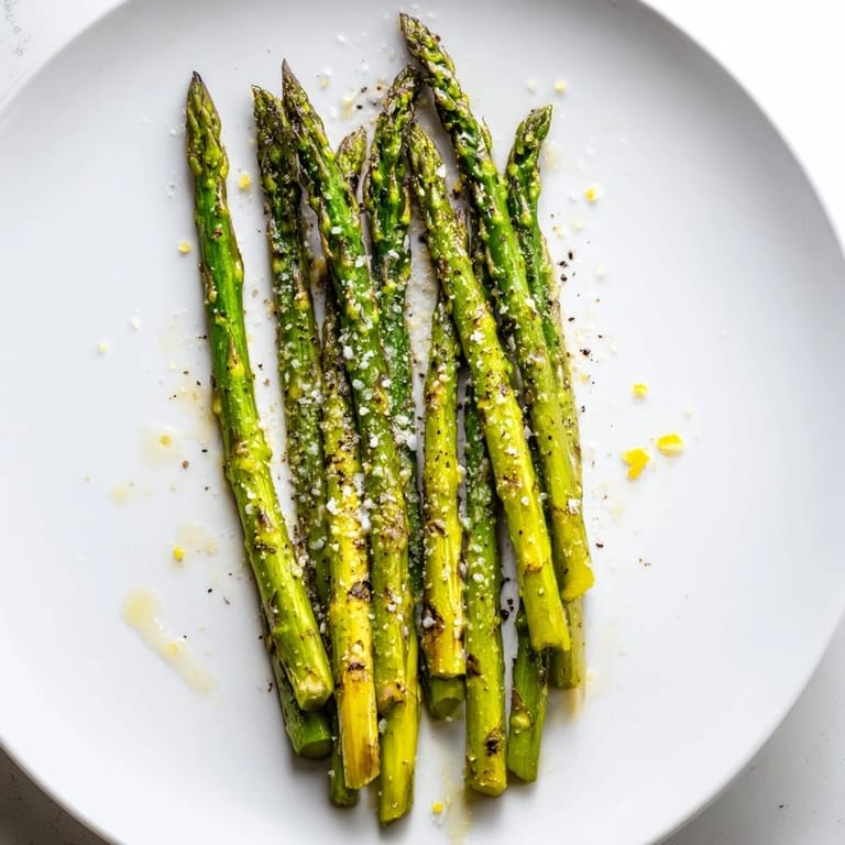 Smoky char marks on perfectly grilled asparagus, seasoned with sea salt and ready to eat.