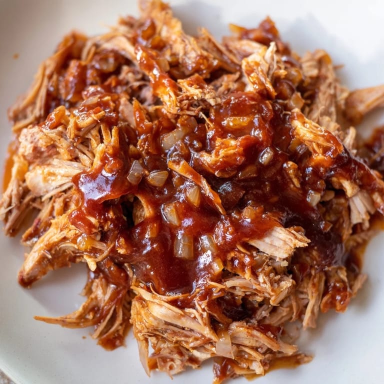 Shredded BBQ pulled chicken, a slow-cooker classic, piled high with smoky aroma and flavor.