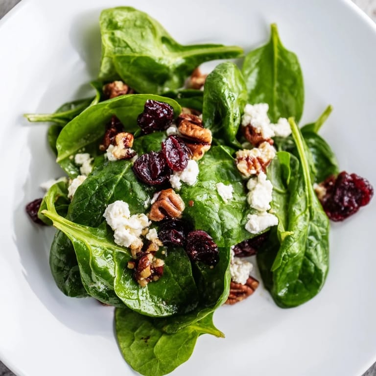 Spinach Goat Cheese Salad featuring candied pecans tossed in a tangy balsamic vinaigrette on a rustic wooden table.