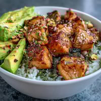 Vibrant avocado salmon bowl with tender marinated salmon, creamy avocado, and crunchy roasted peanuts drizzled with spicy chili oil.